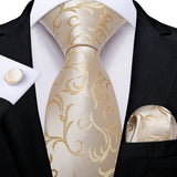 Gold patterned tie with matching pocket square and cufflinks on a black suit.