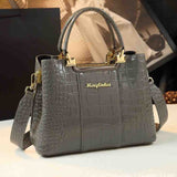 Stylish grey handbag with a crocodile texture, gold accents, and a detachable shoulder strap, showcasing elegance and functionality.