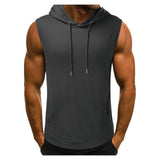 Man wearing a sleeveless dark gray hoodie with a front pocket and drawstrings. His muscular arms are visible. The mood is casual and sporty.