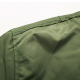 Close-up of an olive green fabric with visible stitching, possibly part of a garment. The texture is smooth, conveying a simple and functional design.