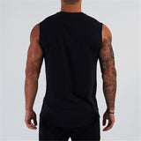 A muscular man with tattoos wearing a sleeveless black shirt, seen from the back against a plain gray background.